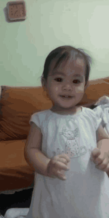 a little girl in a white dress with a cat embroidered on it