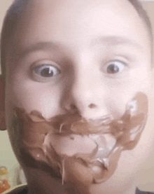 a young boy with chocolate on his face makes a funny face