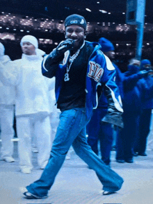 a man wearing a blue jacket with the letter h on it is singing into a microphone