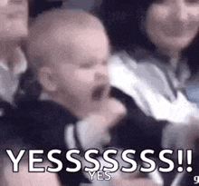a baby is screaming in a crowd of people while a woman holds it .