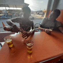 a man is pouring a drink into a glass while another man looks on