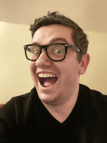 a man wearing glasses and a black shirt makes a funny face