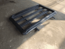 a black roof rack is sitting on a cement floor