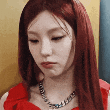 a woman with red hair is wearing a necklace and a red dress