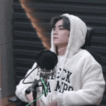 a man in a hoodie is sitting in front of a microphone