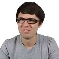 a man wearing glasses and a grey shirt making a sad face