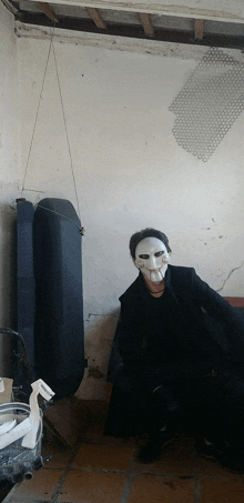 a man wearing a puppet mask sits in a dark room