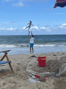 a man throws a child in the air on a beach