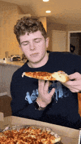 a young man eating a slice of pizza while wearing a watch and a shirt that says ' i love you '