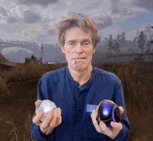 a man in a blue shirt is smoking a cigarette while holding two balls in his hands