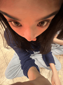 a woman in a blue sweater sits on the floor with her legs crossed