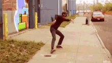 a man is doing a trick on a sidewalk in front of a building with a mural on it .