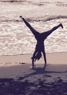 a person is doing a handstand on the beach