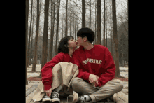 a man and a woman kissing while wearing red sweatshirts that say ' soever that ' on them