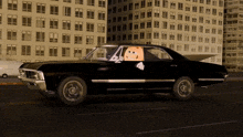 a black car with a cartoon character sticking his head out the window