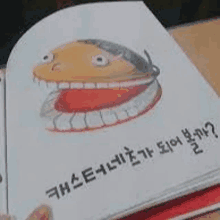 a person is holding a book with a picture of a hamburger on the cover and a foreign language written on it .