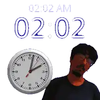 a man with glasses stands next to a clock that says 2:02 am