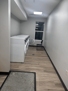 a laundromat with a row of washing machines and a chair