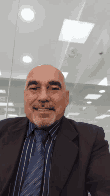 a man in a suit and tie is smiling in front of a glass wall