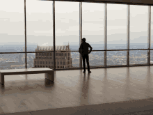 a person standing in front of a large window with a city in the background