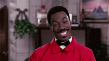 a man wearing a red jacket and a bow tie is smiling .