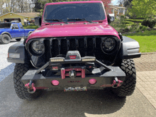 a pink jeep with a warn bumper is parked