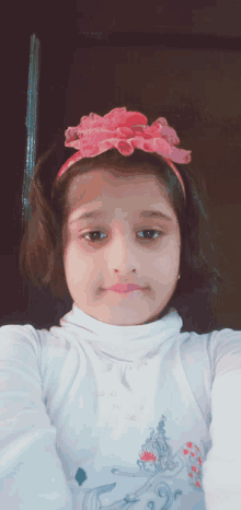 a young girl wearing a white shirt and a pink headband takes a selfie