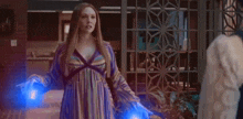 a woman in a striped dress is holding two blue lights in her hands while standing next to a man .