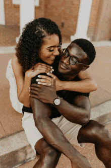 a man wearing glasses holds a woman in his arms