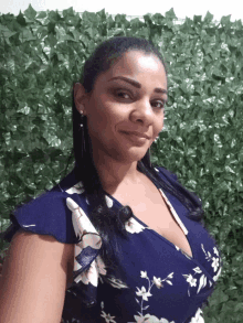 a woman wearing a blue and white floral dress smiles for the camera