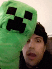 a man is holding a green creeper puppet in his hand