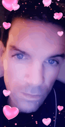 a close up of a man 's face with pink hearts surrounding it