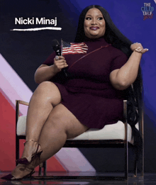nicki minaj is sitting in a chair holding an american flag and a microphone