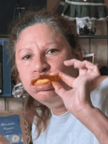 a woman is eating a piece of food with her tongue sticking out while wearing a shirt that says ok life