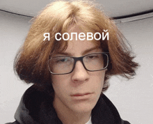 a young man wearing glasses and a black hoodie has a caption in russian on his face