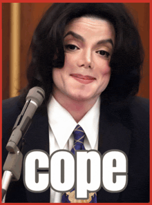 a man in a suit and tie stands in front of a microphone that says cope