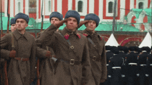 a group of men in military uniforms salute in front of a building that says ' russia 2004 ' on it