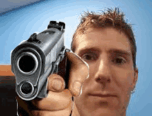 a man is pointing a gun at the camera while taking a selfie .