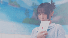 a girl holding a card with a red heart on it