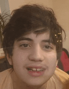 a close up of a young man 's face with a piercing in his forehead and missing teeth .