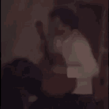 a man in a white shirt is standing next to a woman in a white shirt in a dark room .
