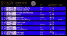 a blue and white departures board with a clock on top