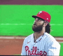 a man wearing a phillies jersey stands on the field