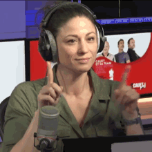 a woman wearing headphones giving a thumbs up in front of a sign that says " cauet et sa team "