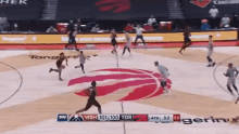 a basketball game is being played on a court with a toronto raptors logo on the court