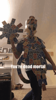 a person holding up a stack of uno cards with the caption " you 're dead mortal " on the bottom