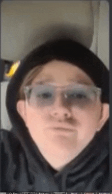 a man wearing a black hoodie and glasses is making a funny face