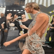 a woman in a very revealing dress is walking on a red carpet while a man holds a microphone .