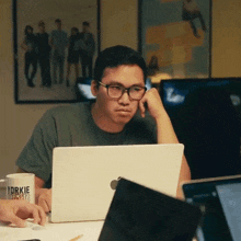 a man wearing glasses sits at a desk with a laptop and a cup that says ' sparkle ' on it