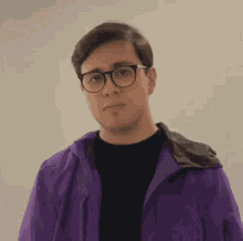 a young man wearing glasses and a purple jacket is making a face .